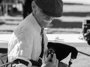 A elderly man fidgets with his bagpipes at the Scottish Festival.