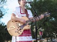 Woman plays guitar in a red and white dirndl dress at Oktoberfest.