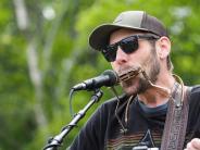 One male plays the harmonica into a microphone.