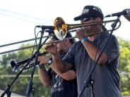 A man plays the trombone on stage outside. 